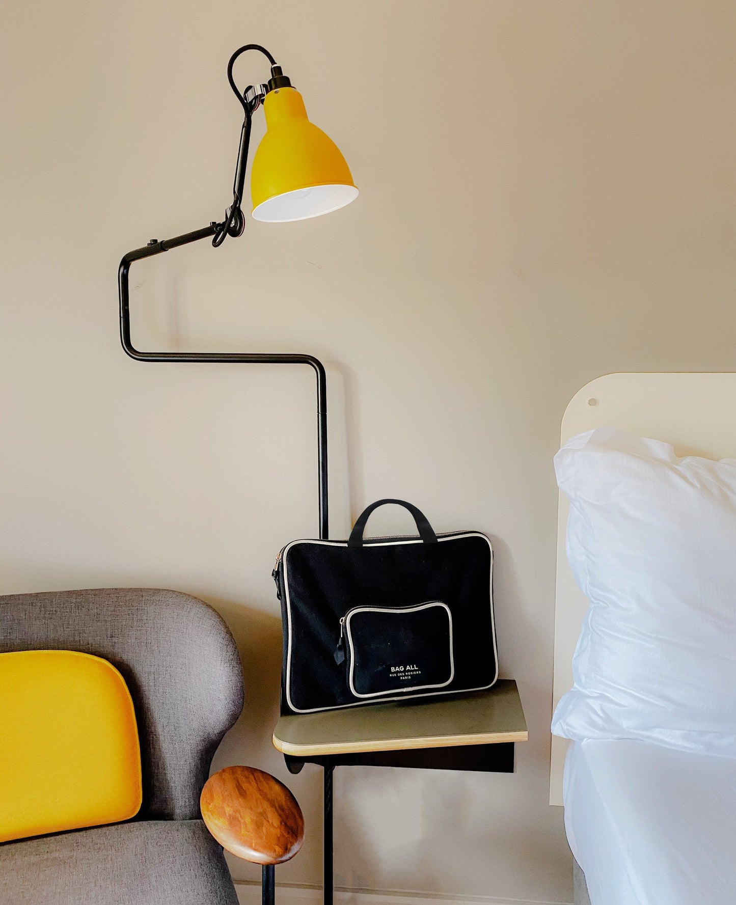 Bag-all Black Laptop Case with Charger Pocket, stylish protective sleeve featuring gold-plated zippers and external storage, shown under yellow desk lamp with minimalist decor