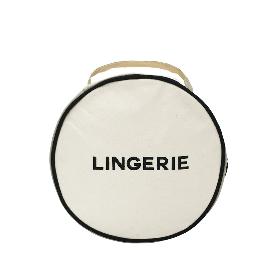 Bag-all Round Lingerie Case in cream canvas with black trim, featuring bold LINGERIE text, double zipper pulls and top handle for elegant travel organization
