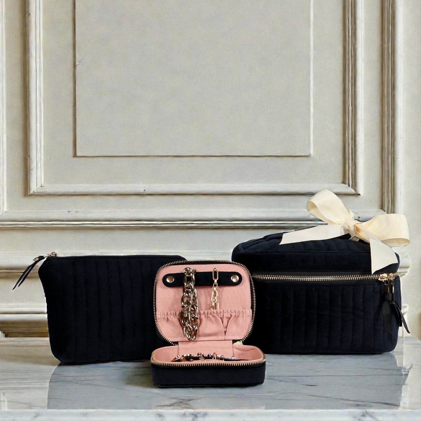 Three-piece black eco-velvet Bag-all set with pink interior jewelry case and beige ribbon on marble surface