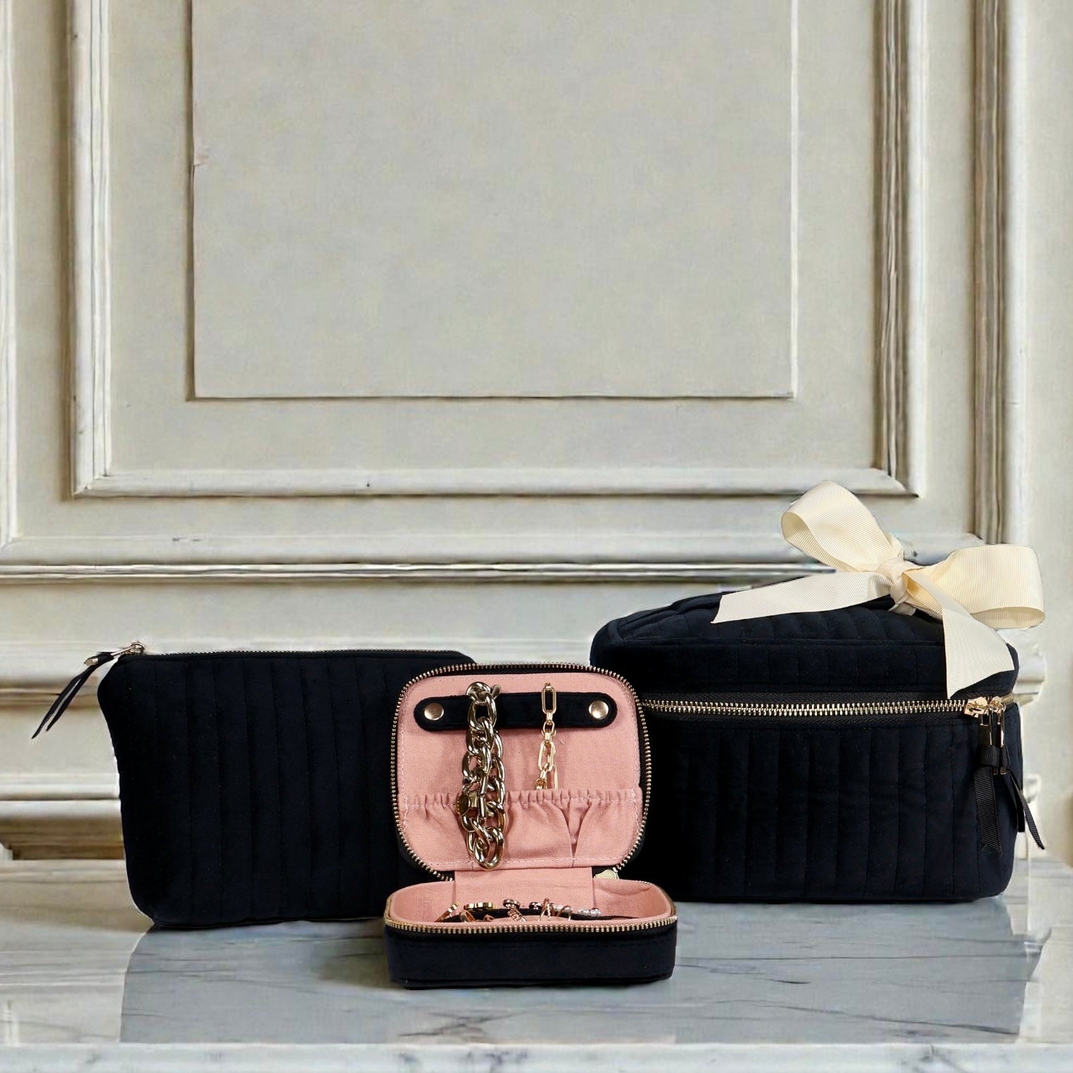 Three-piece black eco-velvet Bag-all set with pink interior jewelry case and beige ribbon on marble surface
