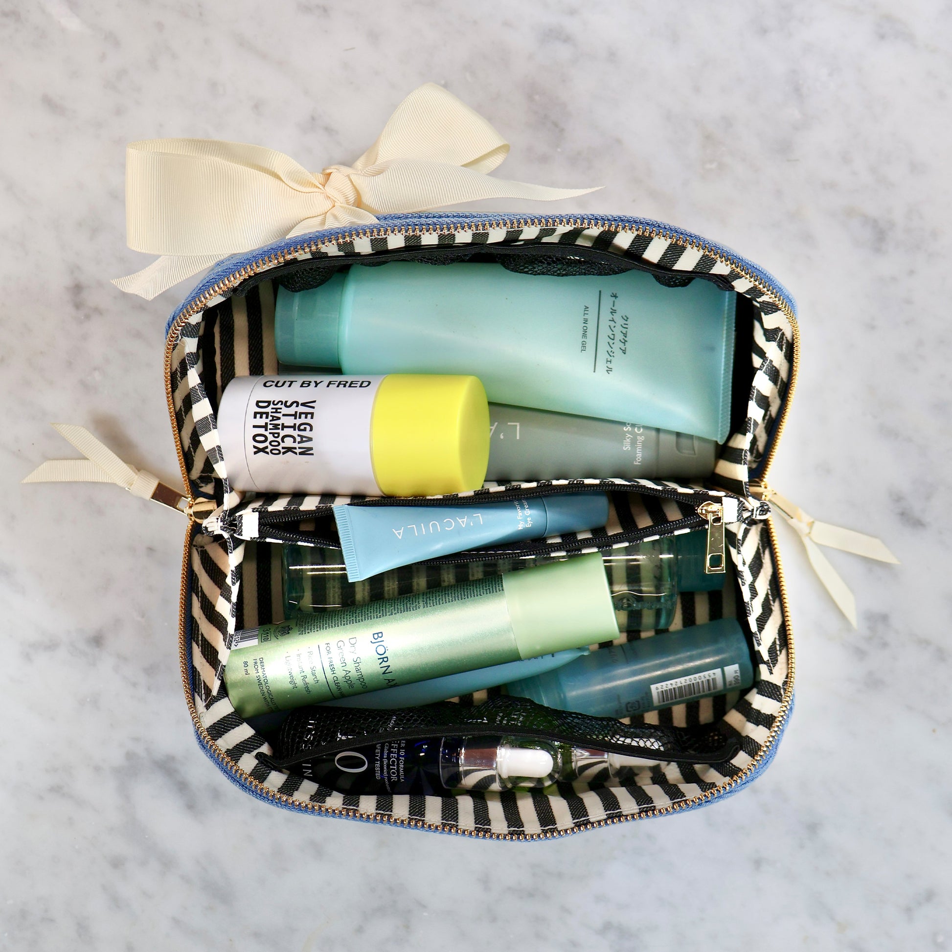 Bag-all expandable denim makeup bag with striped interior, neatly holding skincare and beauty products for easy organization