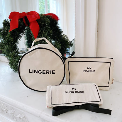 Cream colored Bag-all 3-pack gift set with lingerie, makeup, and jewelry cases displayed near holiday wreath