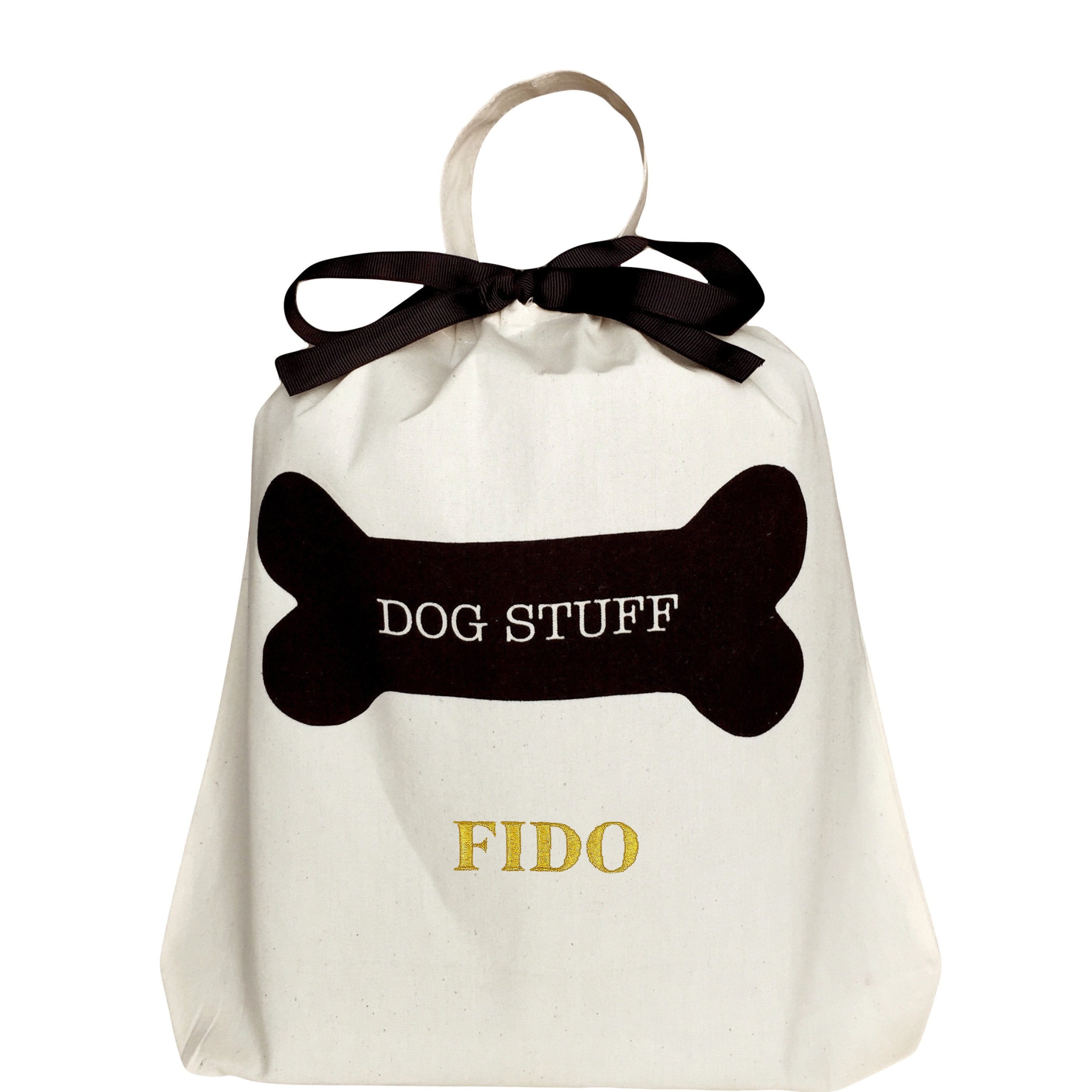 Bag-all Dog Stuff Bag in cream cotton with black bone design and customizable name. Features elegant black bow and handle for pet accessories storage.