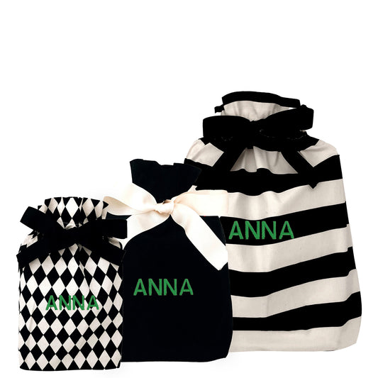 Three Bag-all gift bags set with black and white patterns personalized with the name Anna in green letters