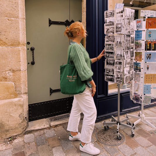 Bag-all Paris Le Marais green linen tote with zipper and inside pocket, shown styled on cobblestone street with vintage postcard display, featuring practical everyday design for urban lifestyle