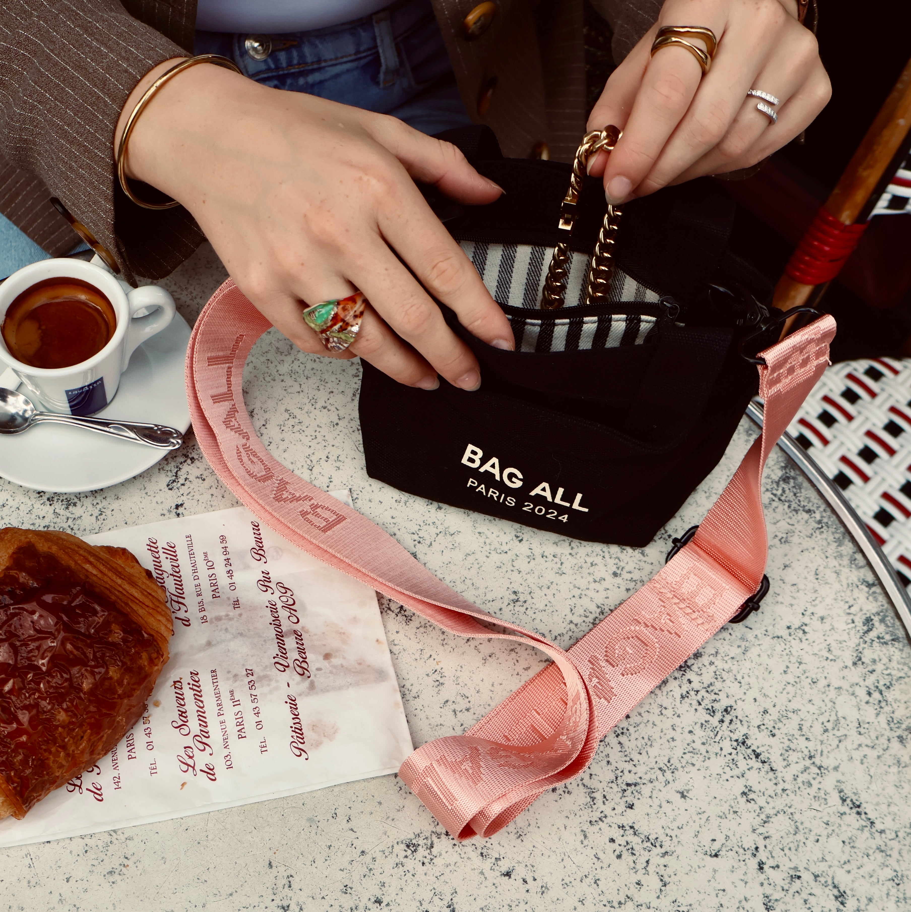 Bag-all Mini Tote Bag with Strap in black being showcased at a cafe table with coffee and pastries, featuring interior pocket design and adjustable functionality