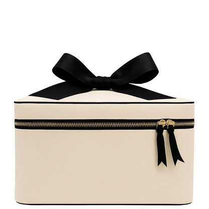 Cream Bag-all makeup and toiletry case with gold zipper and black bow detail for stylish travel and home organization