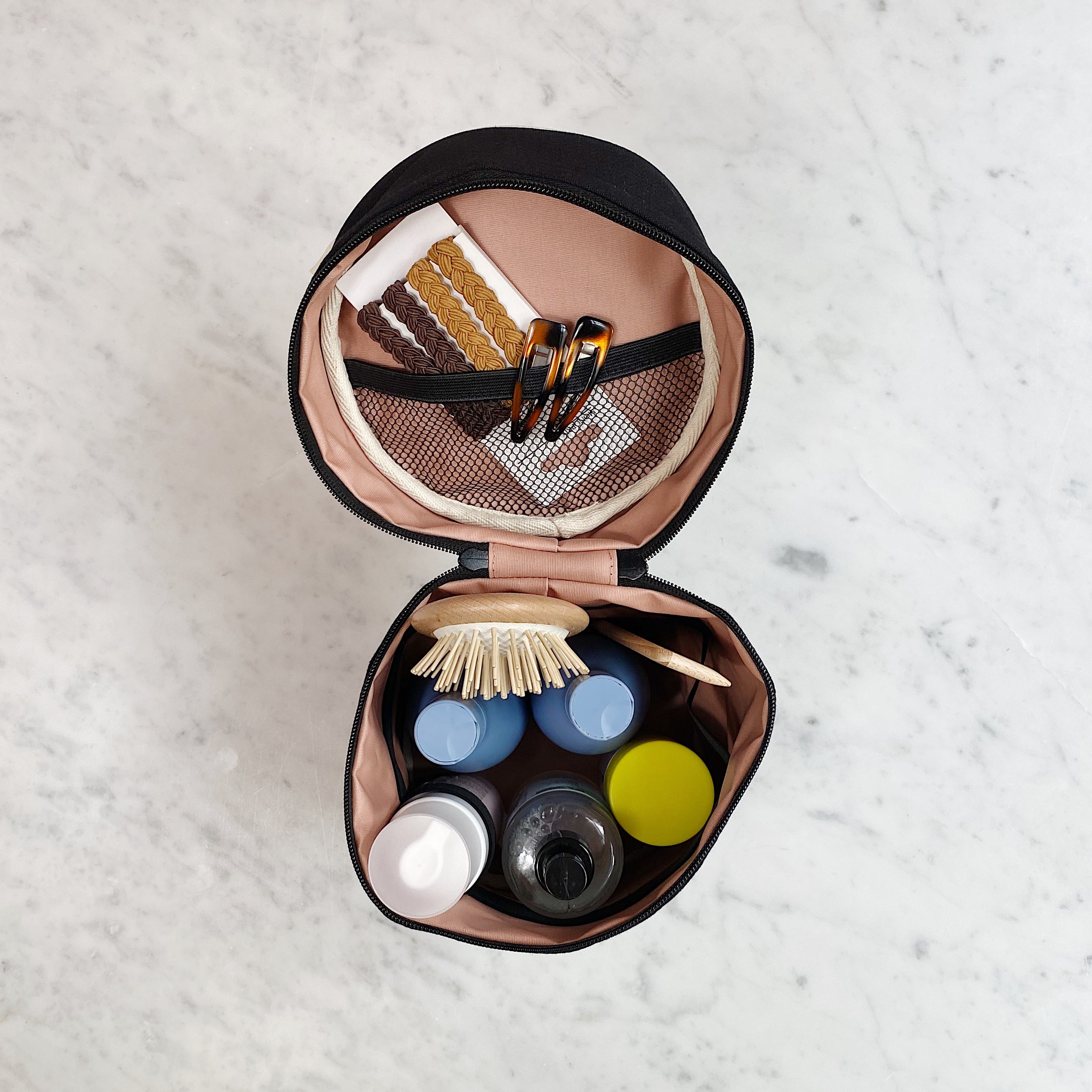 Bag-all Roomy Travel Essentials Case with Coated Lining, Round, Black - open case showing organized toiletries, brushes, and mesh pocket, featuring protective waterproof interior