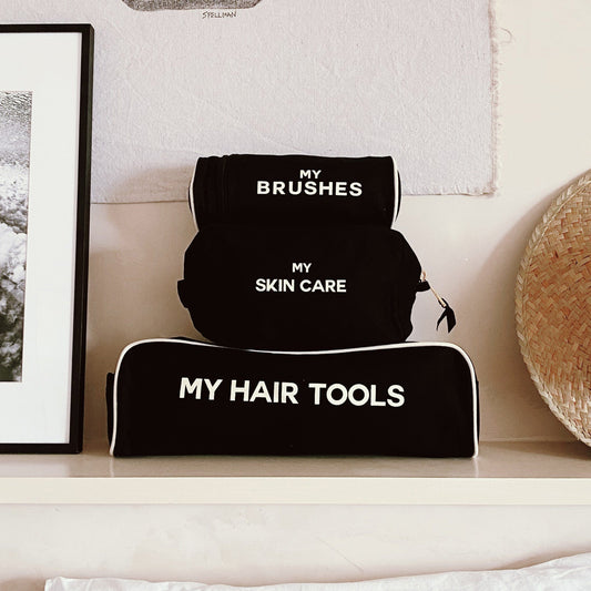 Bag-all Black Pamper Gift Set 3-Pack featuring cotton organizer cases for hair tools, brushes, and skincare, with white contrast text and piping, displayed on white shelf
