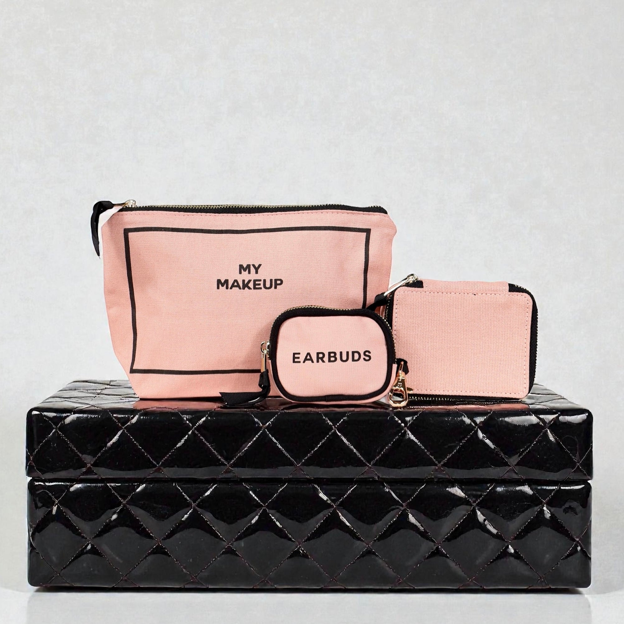Pink Bag-all handbag organizer trio with makeup, earbuds, and trinket cases on black textured box background