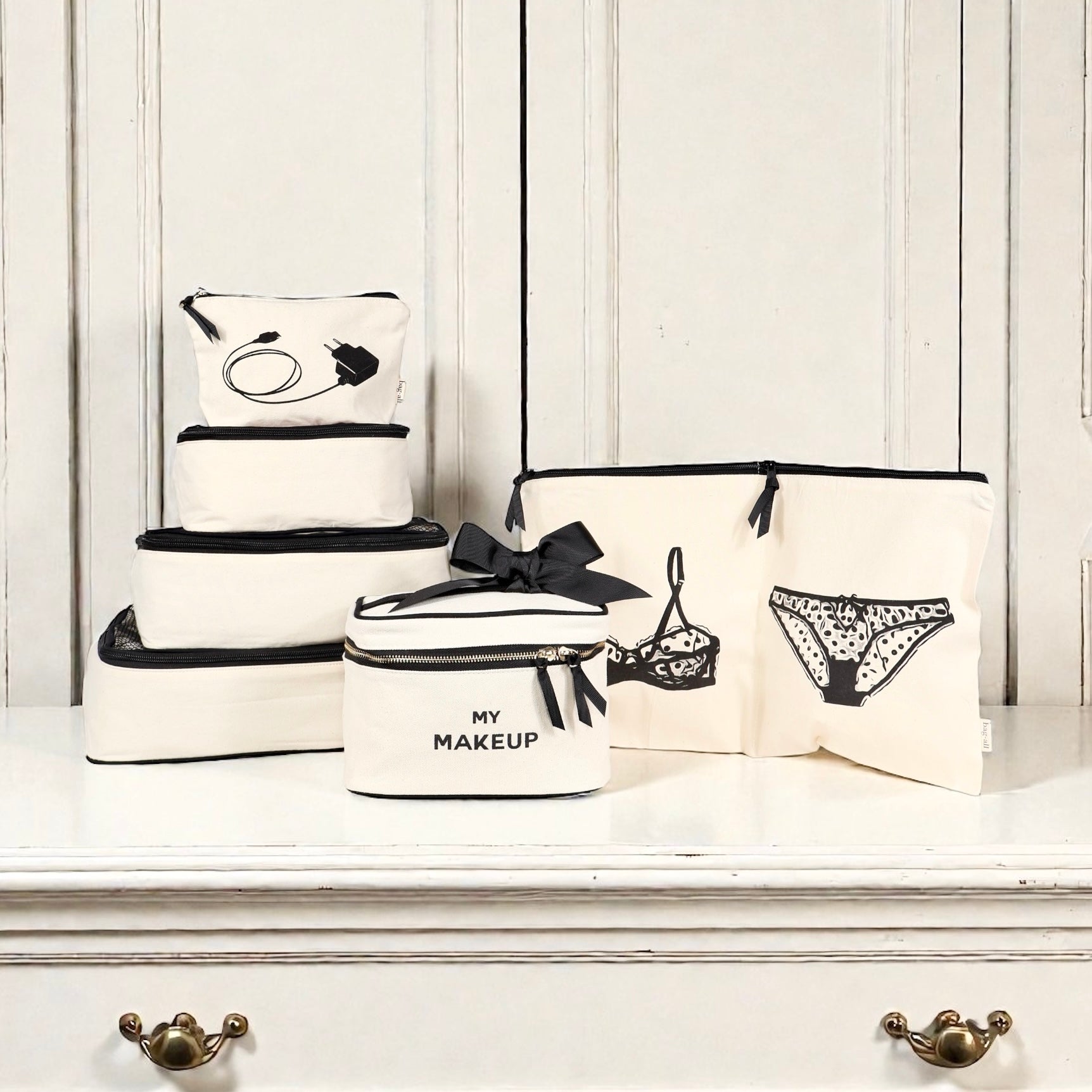 Set of natural cotton Bag-all organizers with black zippers and lingerie, makeup, and tech prints on white background