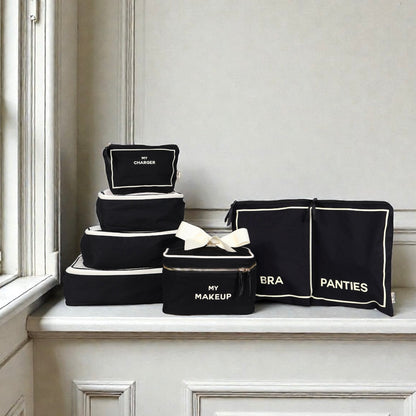 Set of black Bag-all cotton travel organizers with white trim labeled charger makeup bra and panties
