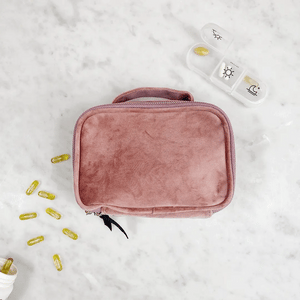 Bag-all Pink Velvet Pill Box with Handle & Weekly Organizer shown with supplement capsules and daily pill container on marble surface, showcasing portable medication storage solution