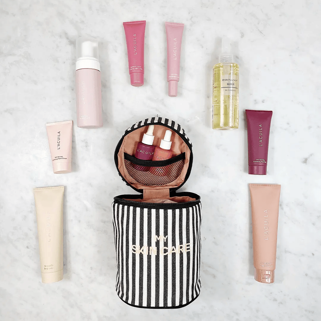 Bag-all Round Skin Care Case with Handle in black and white stripes, shown open with beauty products arranged around it on marble surface, displaying interior mesh pocket and functional storage design