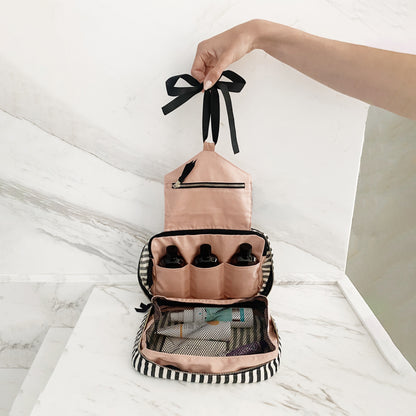 Bag-all striped 3-pack toiletry and skincare organizer open with travel bottles inside on marble surface