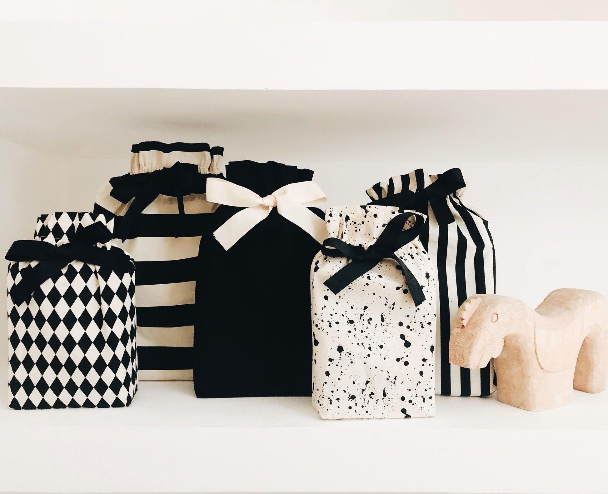 Bag-all Gift Bag Striped Medium collection featuring black and white patterns, including striped, diamond, solid, and splatter designs, with elegant bow details, displayed against white background