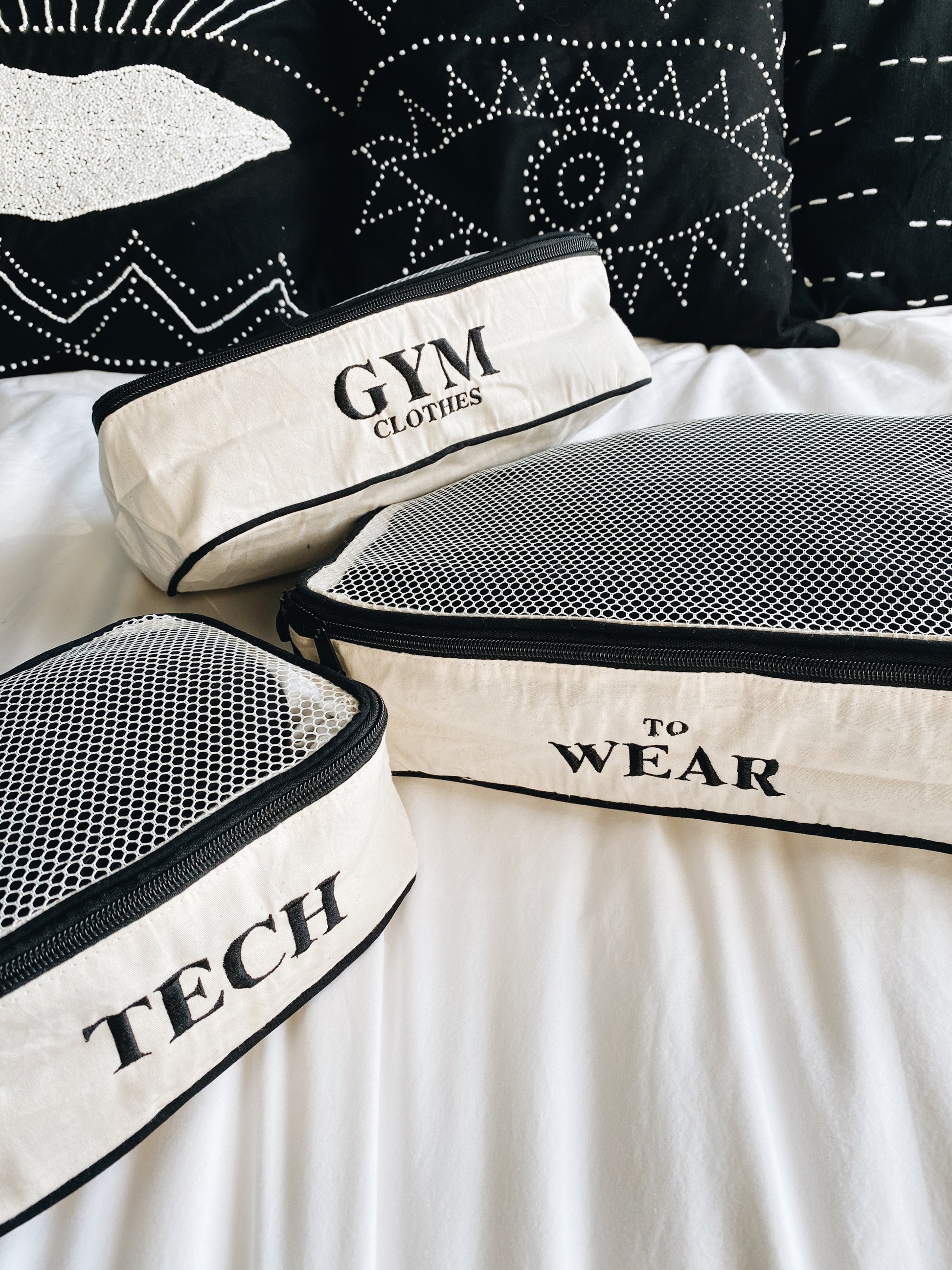 Bag-all monogram customization option shown with organized travel packing cubes labeled 'Gym Clothes', 'To Wear', and 'Tech' in black and white mesh design with clear typography