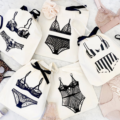 Bag-all lingerie organizing bags featuring stylish black and white illustrations of various lingerie sets on cotton bags with black ribbon ties, perfect for travel and storage