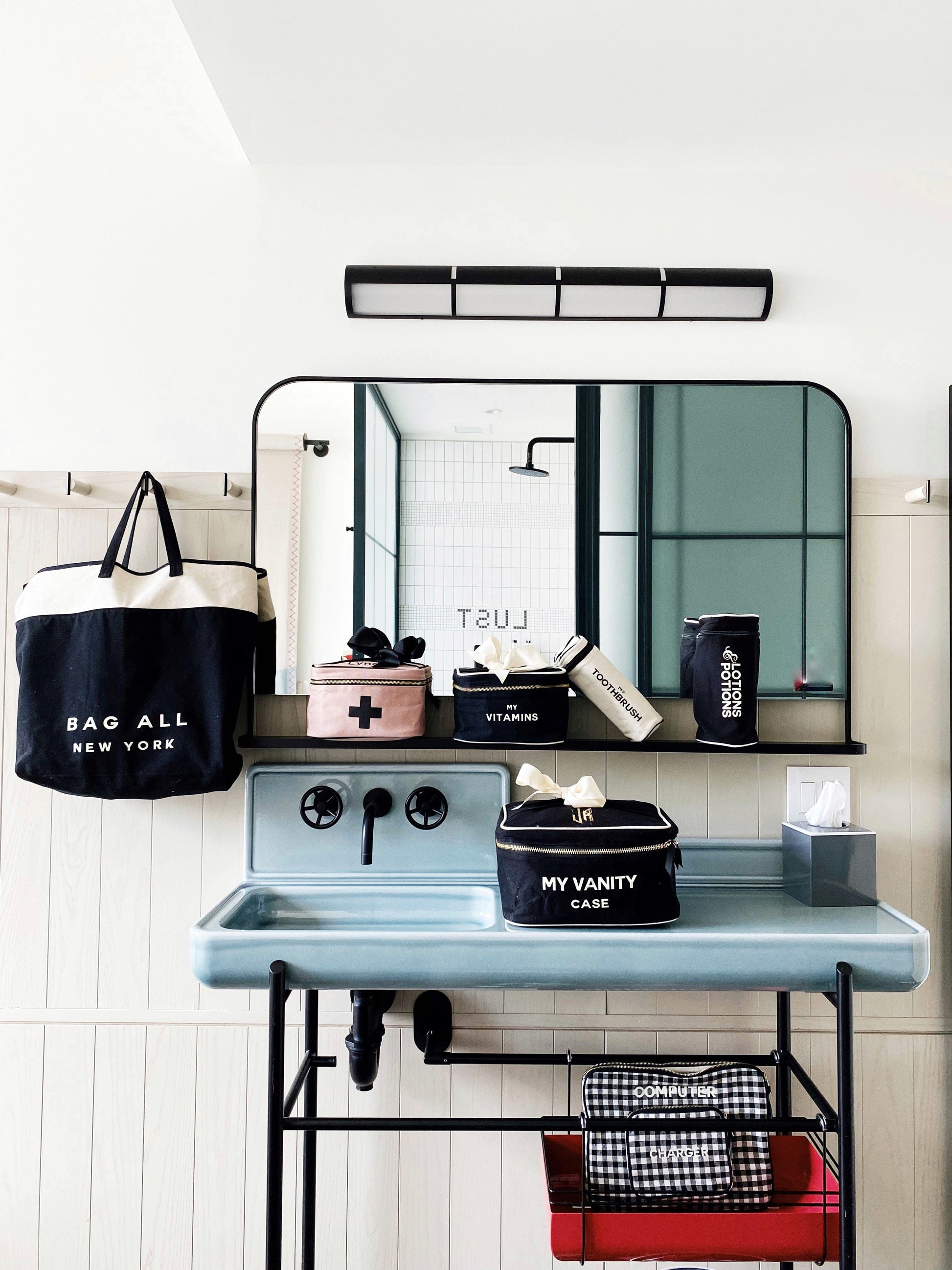 Bag-all Pink First Aid Storage Box with black cross print, shown with other organizing cases in a modern bathroom setting, featuring eco-friendly cotton and striped interior lining