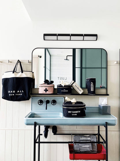 Bag-all Pink First Aid Storage Box with black cross print, shown with other organizing cases in a modern bathroom setting, featuring eco-friendly cotton and striped interior lining