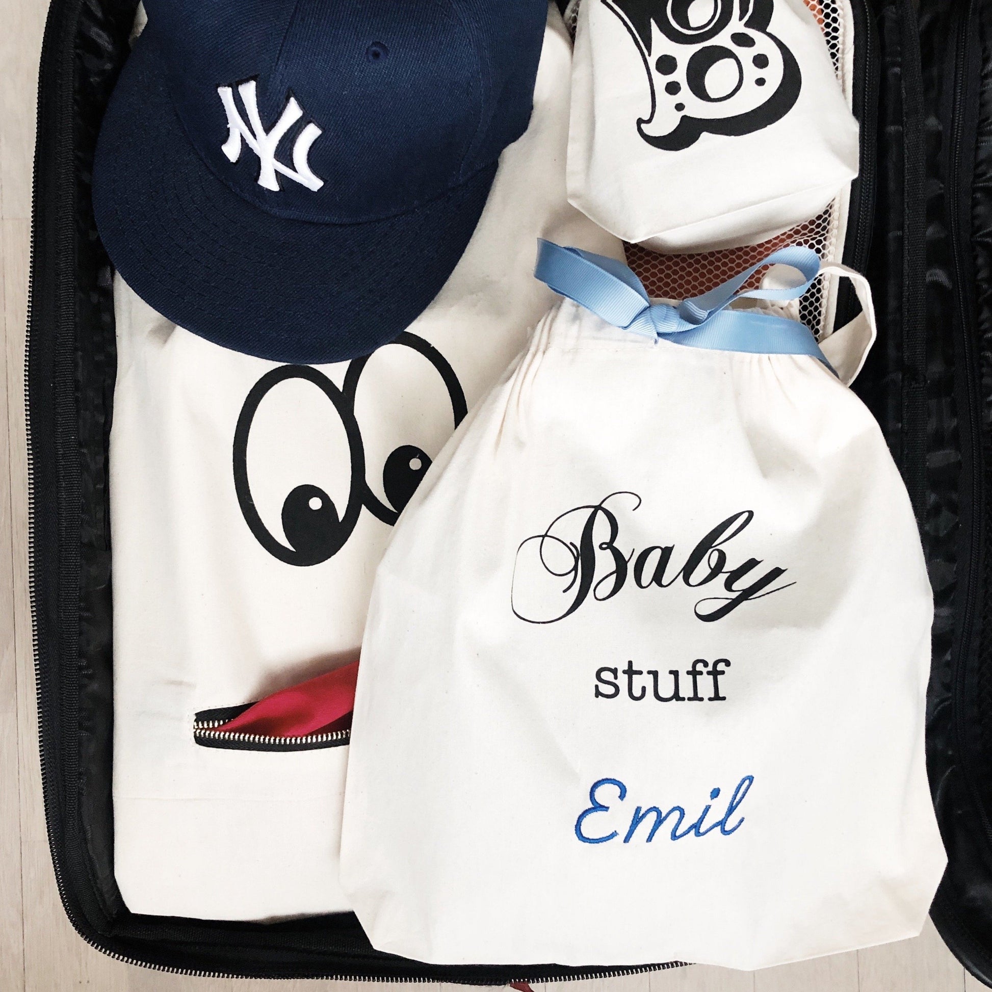 Bag-all personalized Baby Stuff organizer bag with NY Yankees cap, featuring custom name Emil, white cotton drawstring pouch with blue ribbon accent for nursery storage