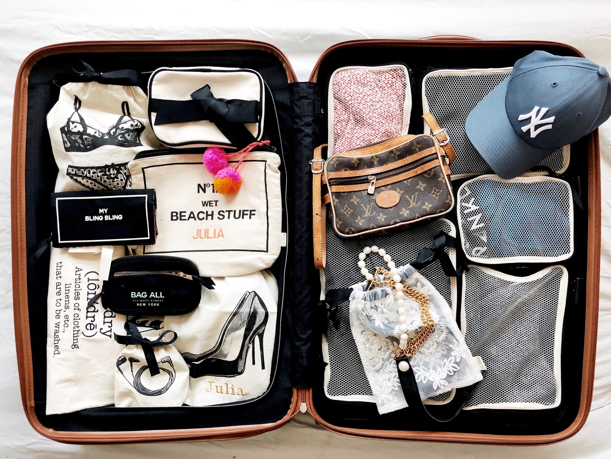 Bag-all Cotton Packing Cubes in black shown organizing travel items in open suitcase with mesh compartments, perfectly sorted clothes and accessories demonstrating space-saving storage