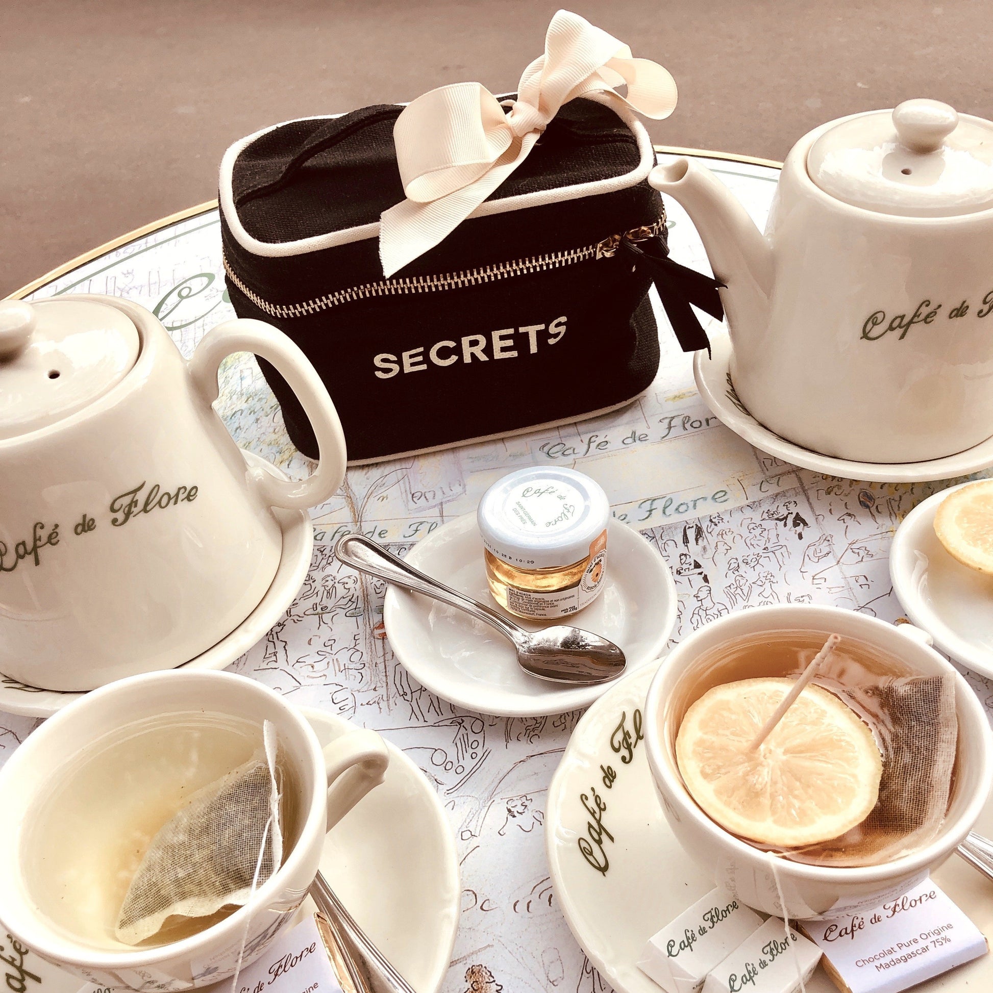 Une table de café avec café et thé avec une mini boîte de beauté secrets sur la table.