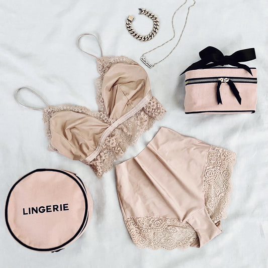 Bag-all Round Lingerie Case in blush pink shown with matching lace lingerie set, showcasing its perfect size and elegant design for organizing delicate undergarments while traveling