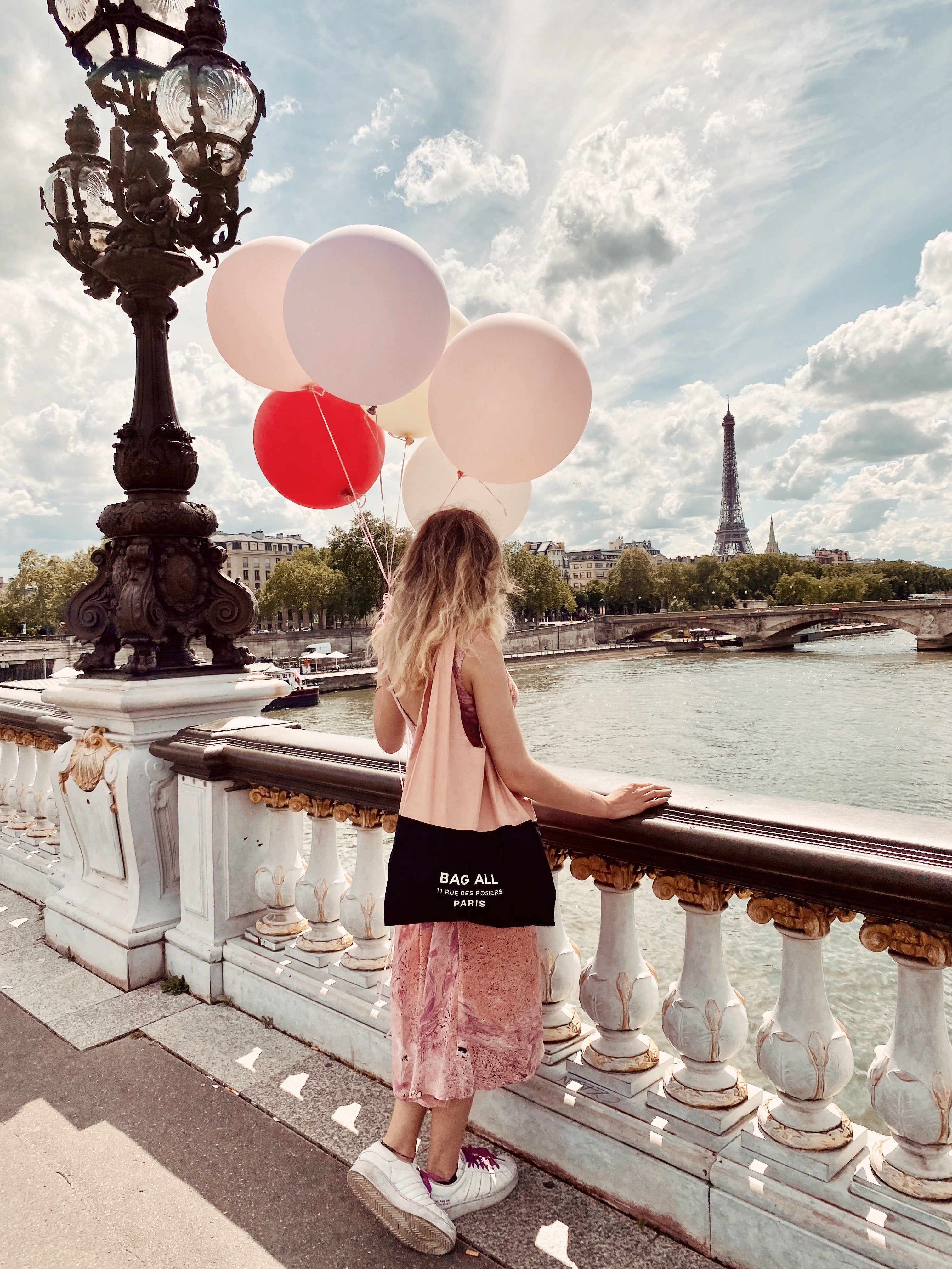 Fille à Paris tenant des ballons avec un sac tout sac fourre-tout.