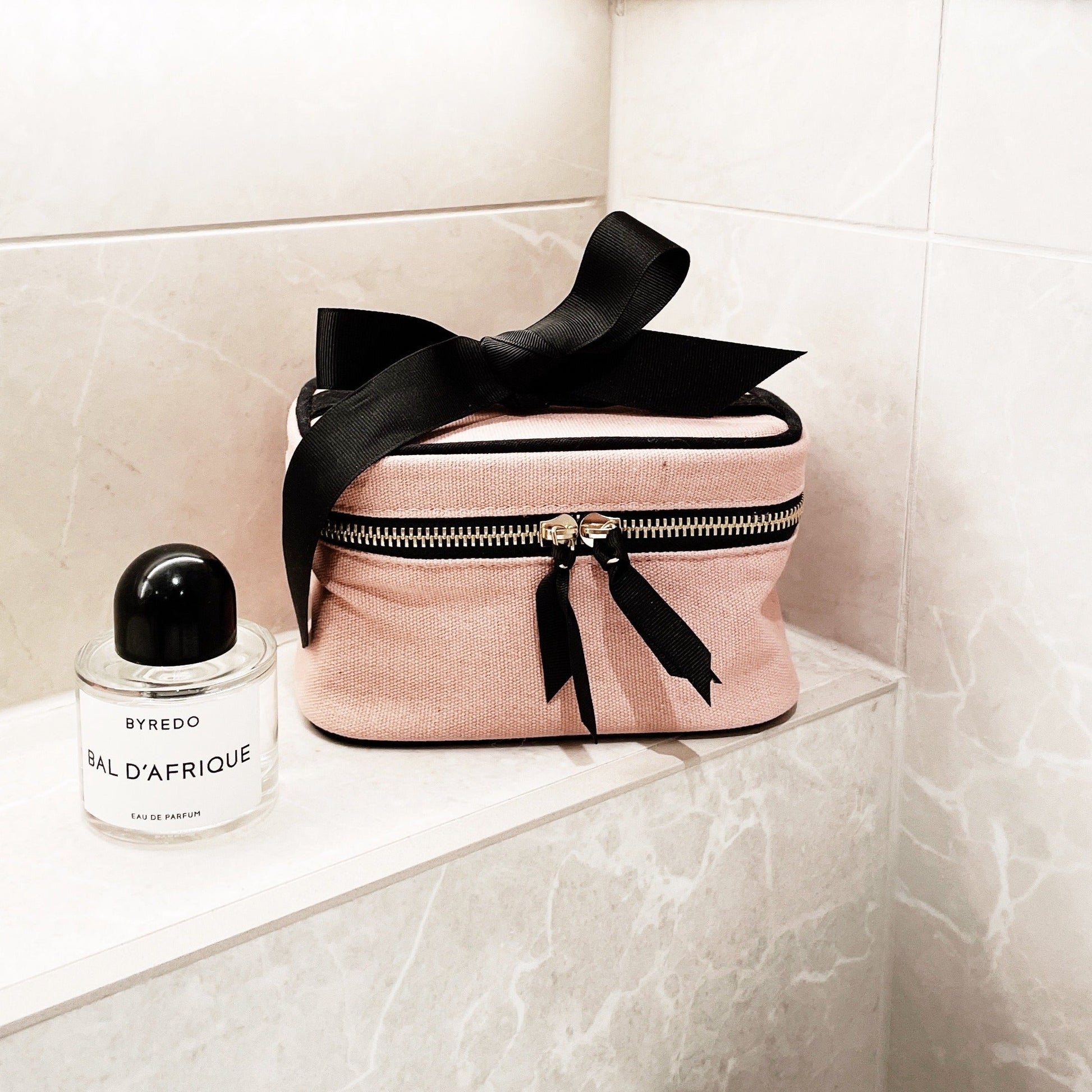 Bag-all pink velvet makeup case with black bow and zipper detail, elegant travel cosmetic organizer for beauty essentials, perfect vanity storage companion