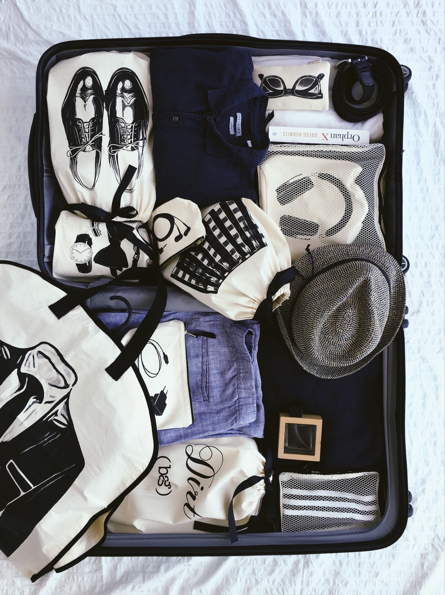 Bag-all Loafers Moccasin Shoe Bag in cream shown in packed suitcase with organized travel essentials including clothing, accessories, and other shoe storage bags in black and white color scheme