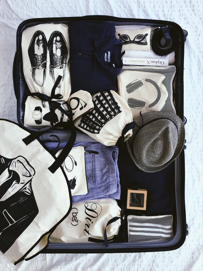 Bag-all Loafers Moccasin Shoe Bag in cream shown in packed suitcase with organized travel essentials including clothing, accessories, and other shoe storage bags in black and white color scheme