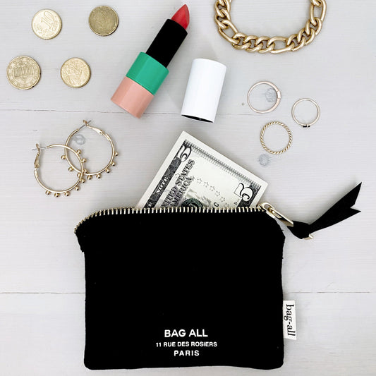 Bag-all Mini Trinket Pouch in Black with everyday essentials displayed - lipstick, jewelry, coins, and cash - showcasing practical storage on white wooden surface