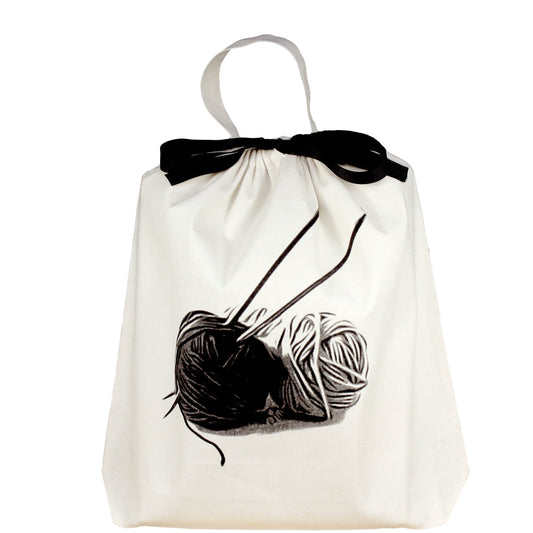 Bag-all Cream Knitting Bag featuring black and white yarn ball illustration with knitting needles, cotton tote with black bow and carrying handle, perfect for organizing craft supplies