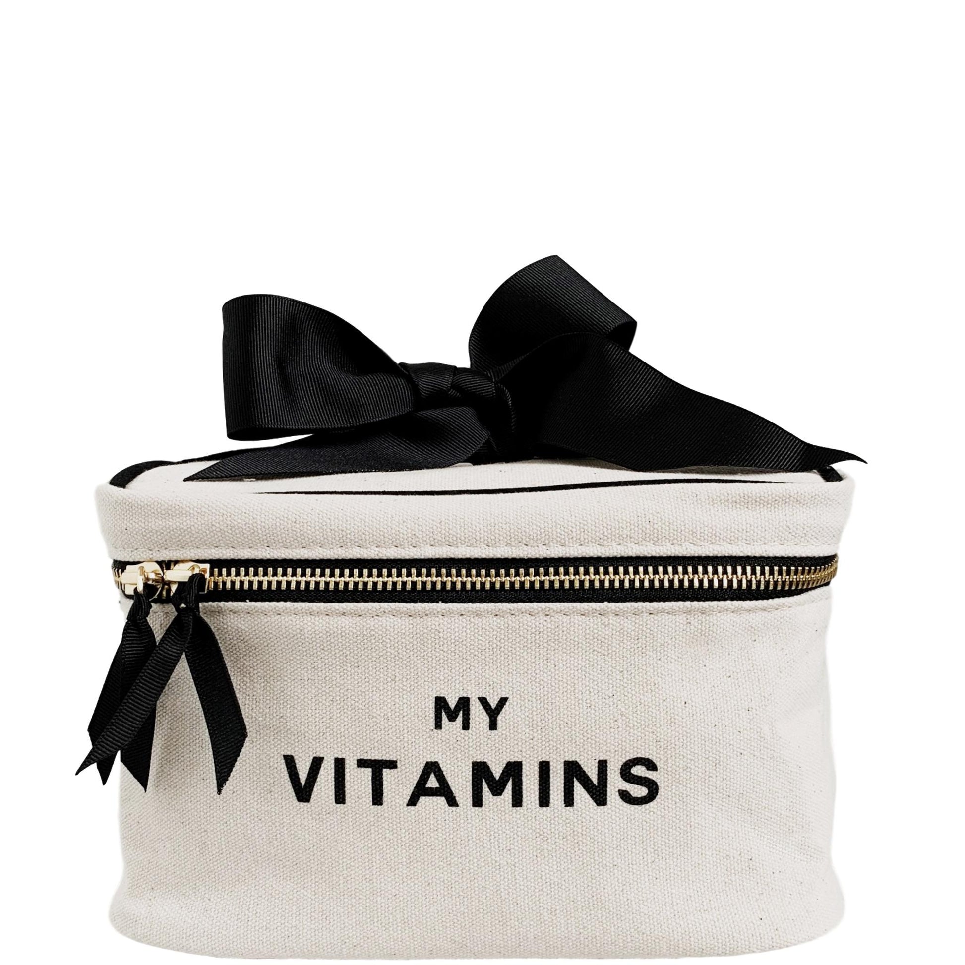 Bag-all Vitamins Storage and Travel Box in cream canvas with black bow, featuring silver zipper and "MY VITAMINS" text, perfect for organizing supplements