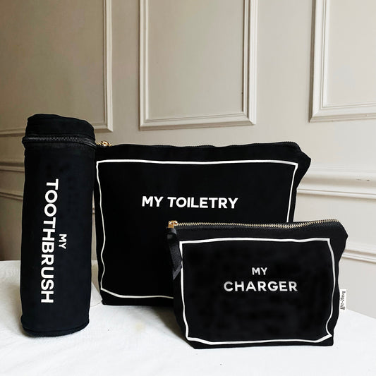 Bag-all black and white travel organizer set featuring toothbrush holder, toiletry bag and charger case with white piping and text labels for organized travel