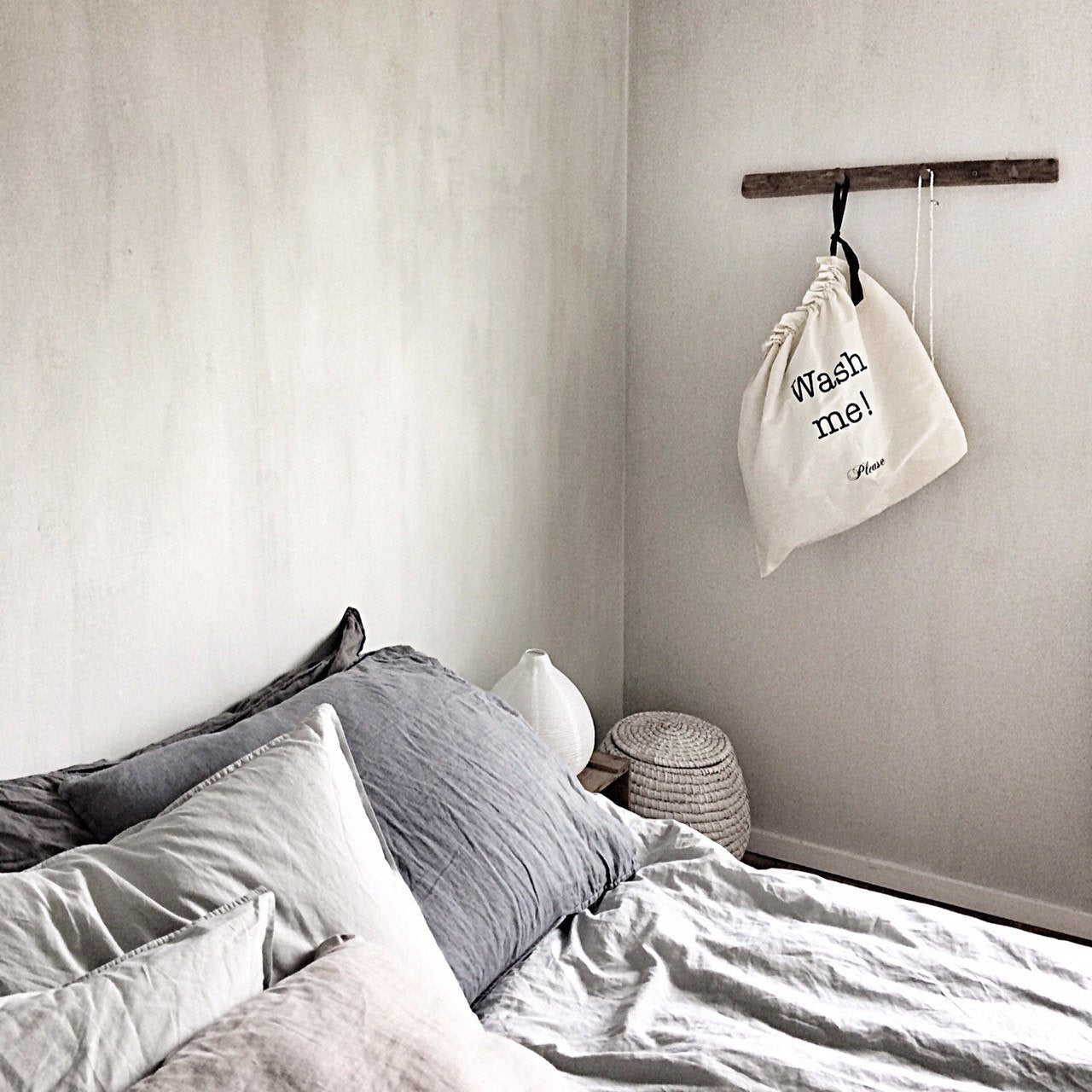 Une chambre avec un grand sac à linge suspendu à un crochet au mur.